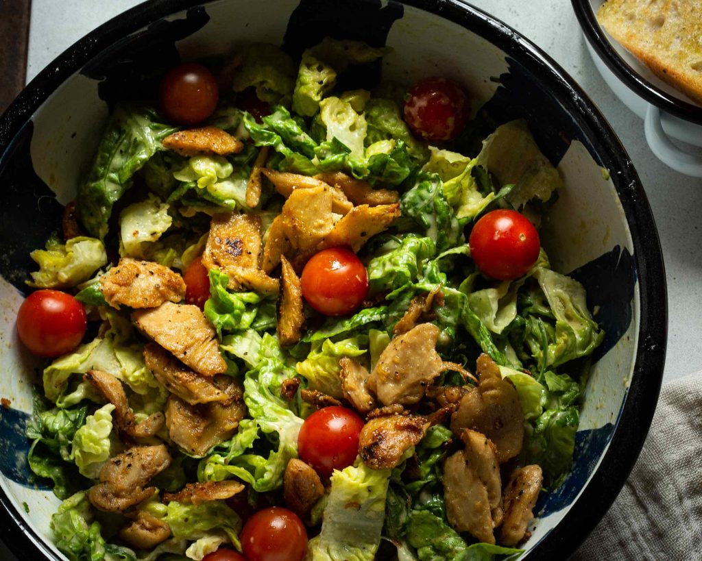 Veganer Caesar Salad mit Römersalat, Cocktailtomaten, knusprigem Chicken-Ersatz und cremigem Dressing – perfekter leichter Sommer-Lunch