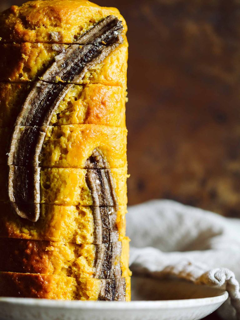 Saftiges Kürbis Bananenbrot mit halbierter Banane auf der Oberfläche, frisch in einer Kastenform gebacken