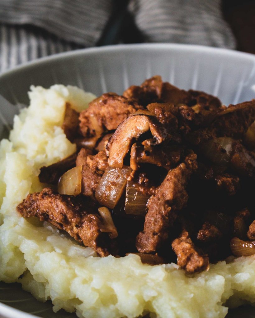 Veganes scharfes Sojageschnetzeltes mit Kartoffelstampf auf Teller serviert