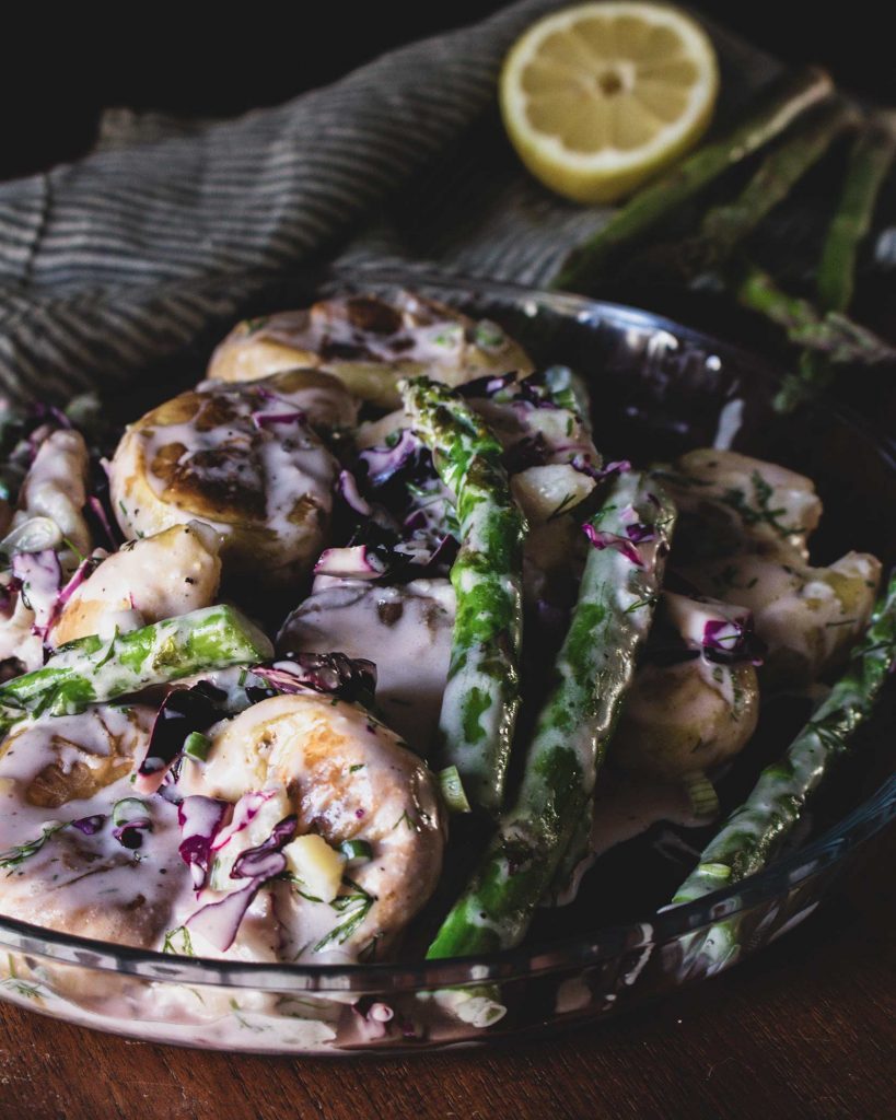 Veganer Kartoffelsalat mit Ofenkartoffeln und grünem Spargel auf Teller serviert