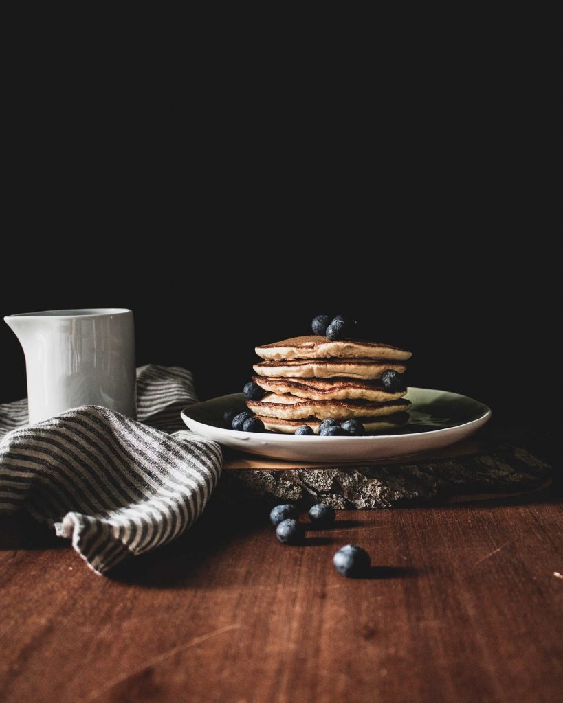 Fluffige vegane Banane Blaubeere Pancakes, gestapelt und mit Ahornsirup sowie frischen Blaubeeren serviert