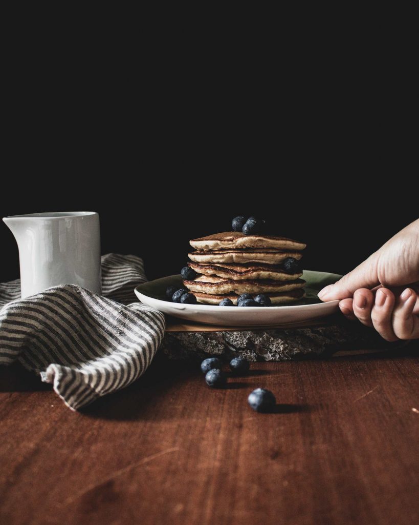 Fluffige vegane Banane Blaubeere Pancakes, gestapelt und mit Ahornsirup sowie frischen Blaubeeren serviert