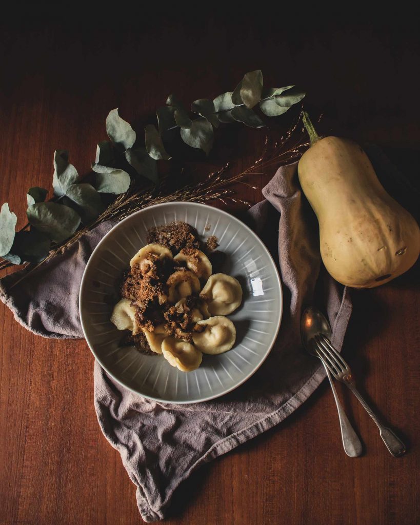 Hausgemachte Tortellini mit Kürbis-Kartoffelfüllung und Butterbröseln, auf einem Teller serviert.