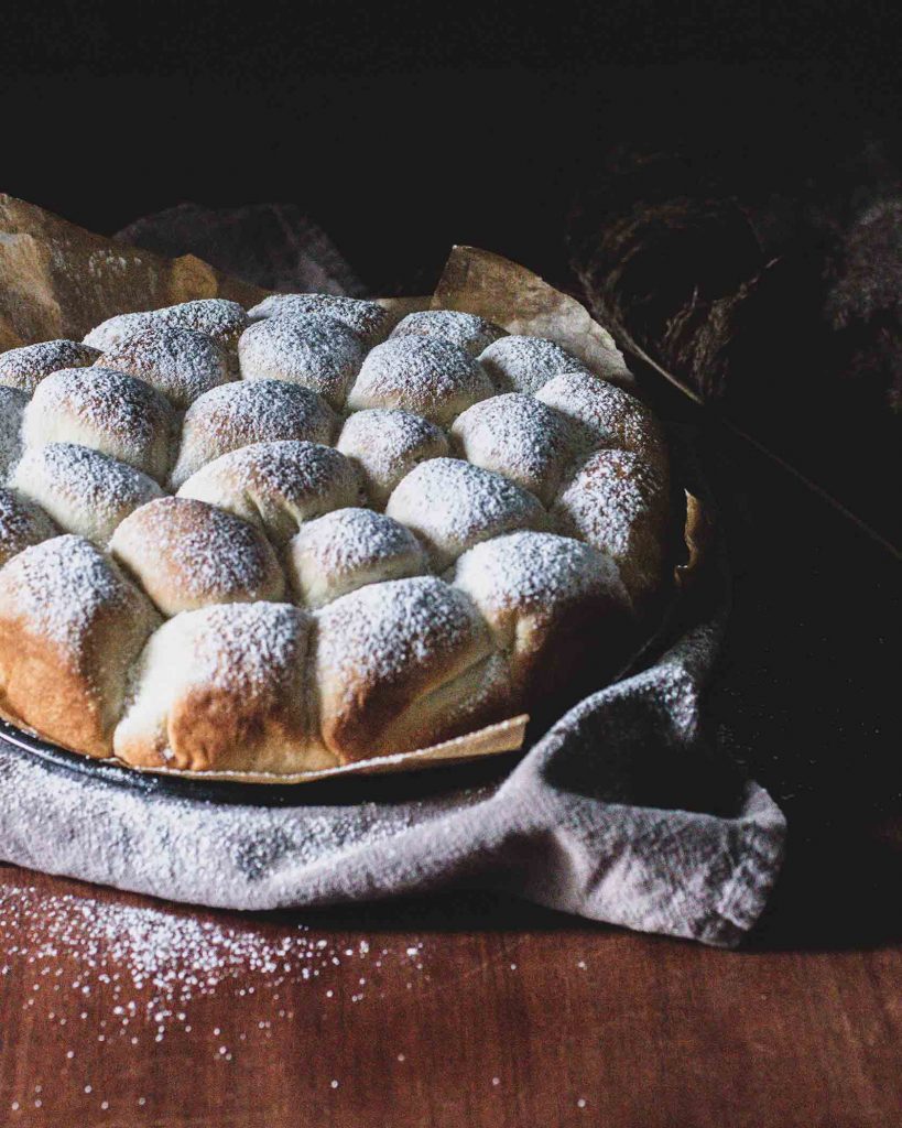 Goldbraune vegane Buchteln dicht aneinander gebacken und mit Puderzucker bestäubt