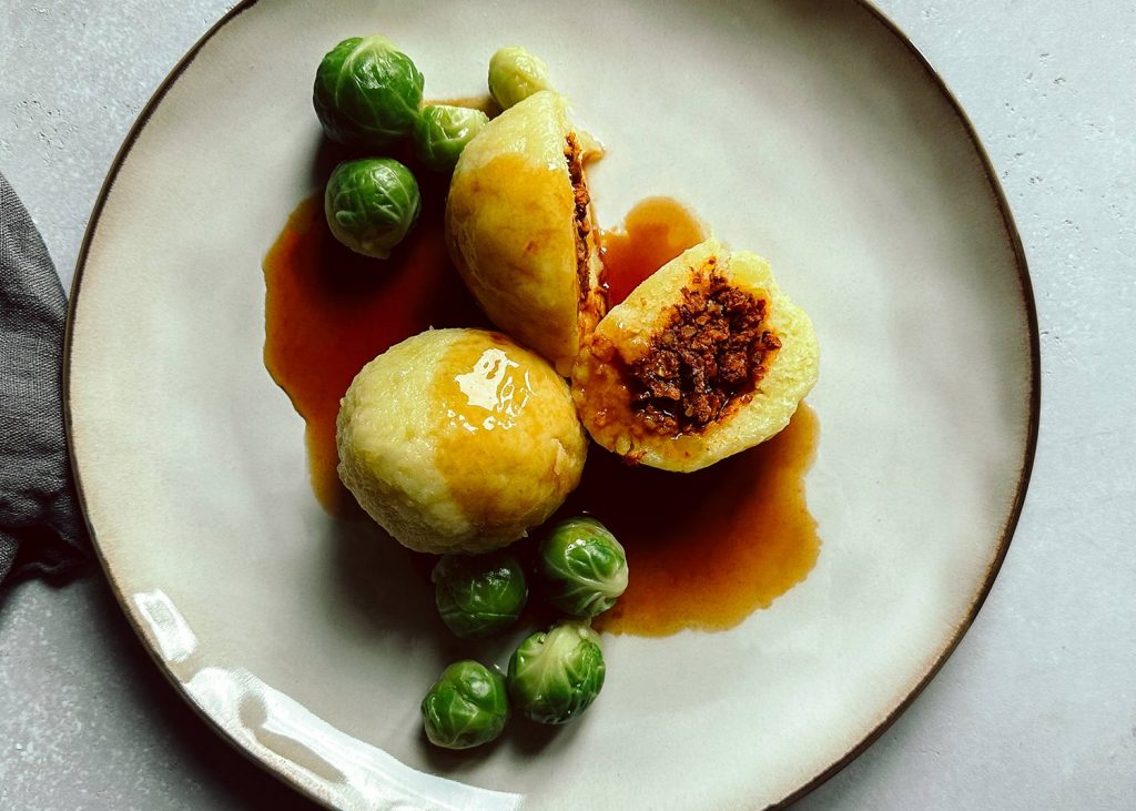 Vegane gefüllte Kartoffelknödel mit Walnuss-Pilz-Füllung auf einem Teller
