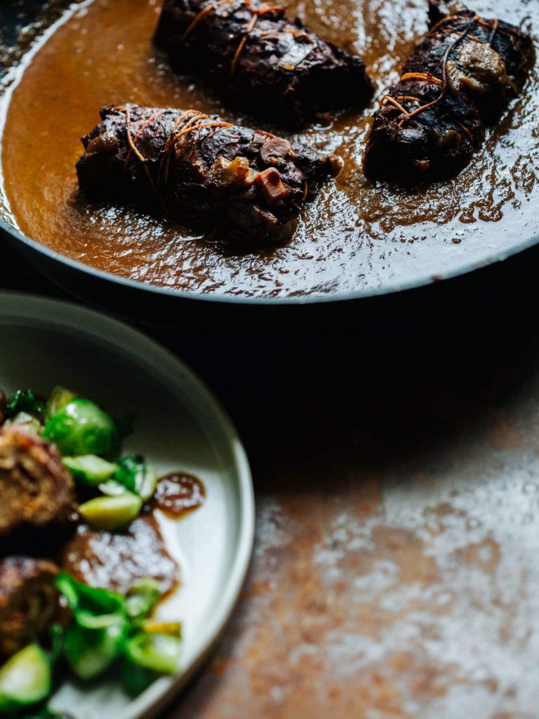 Vegane Rouladen aus Soja mit Füllung und dunkler Bratensauce auf einem Teller serviert