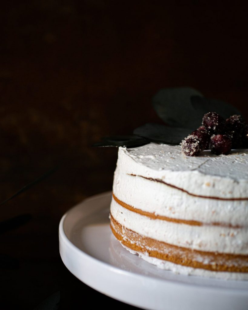 Vegane Torte mit Biskuitboden, weißer Schokoladencreme und Pflaumenmus, dekoriert auf einer Kuchenplatte