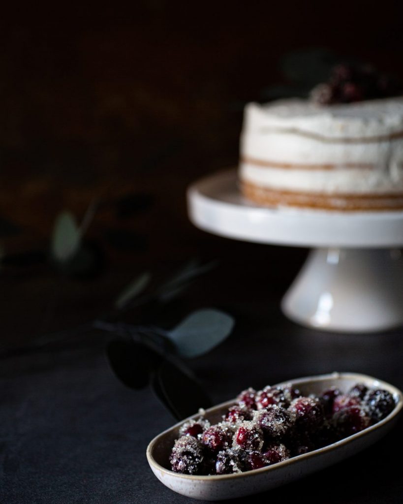 Vegane Torte mit Biskuitboden, weißer Schokoladencreme und Pflaumenmus, dekoriert auf einer Kuchenplatte