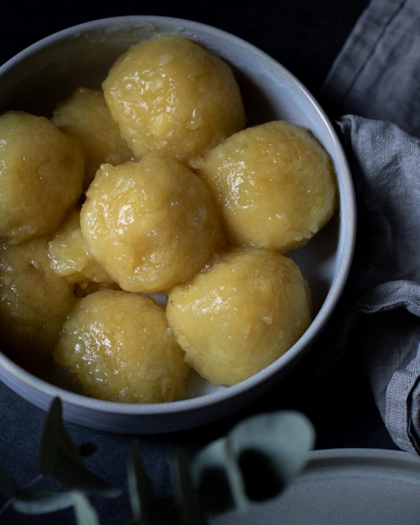 Vegane Kartoffelklöße auf einem Teller, serviert als klassische Beilage.
