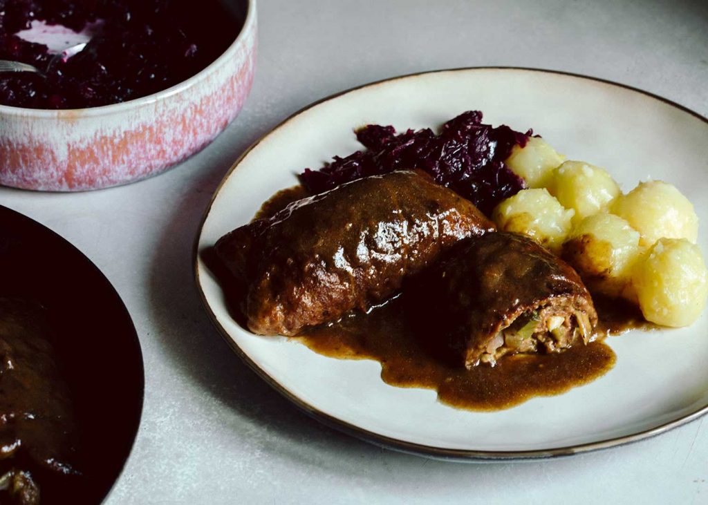 Vegane Rouladen aus Seitan mit Füllung aus Zwiebel, Gurke und Pilzen, serviert mit Rotkohl und Klößen