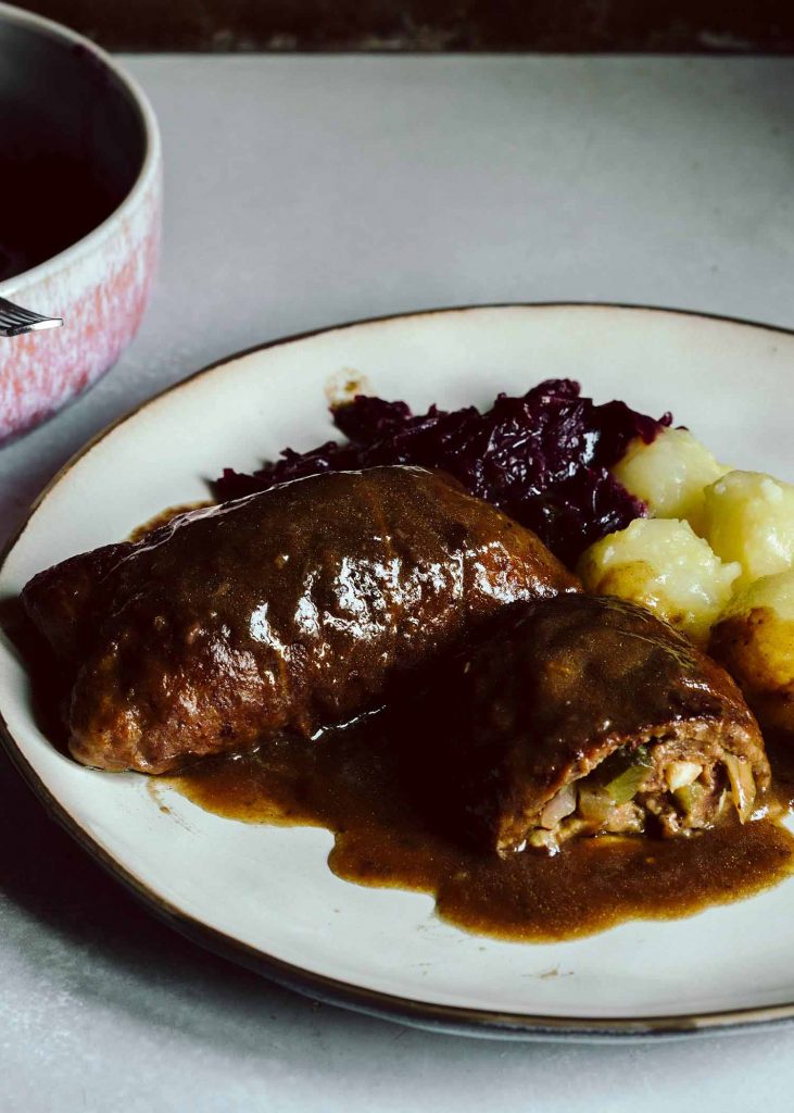 Vegane Rouladen aus Seitan mit Füllung aus Zwiebel, Gurke und Pilzen, serviert mit Rotkohl und Klößen