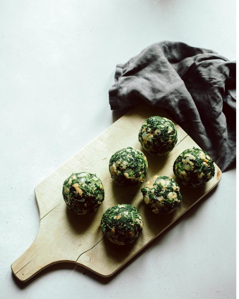 Vegane Spinatknödel serviert mit cremigen Rahmchampignons auf einem Teller