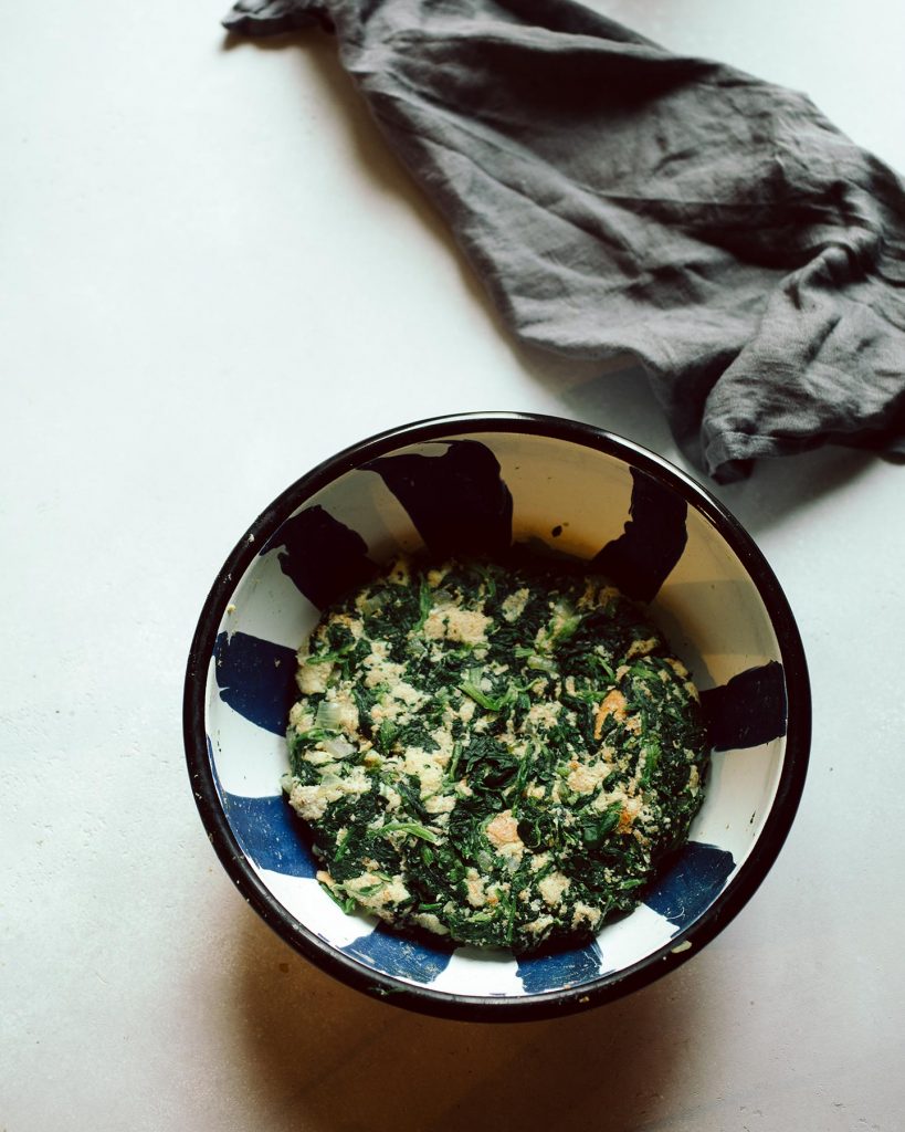 Vegane Spinatknödel serviert mit cremigen Rahmchampignons auf einem Teller