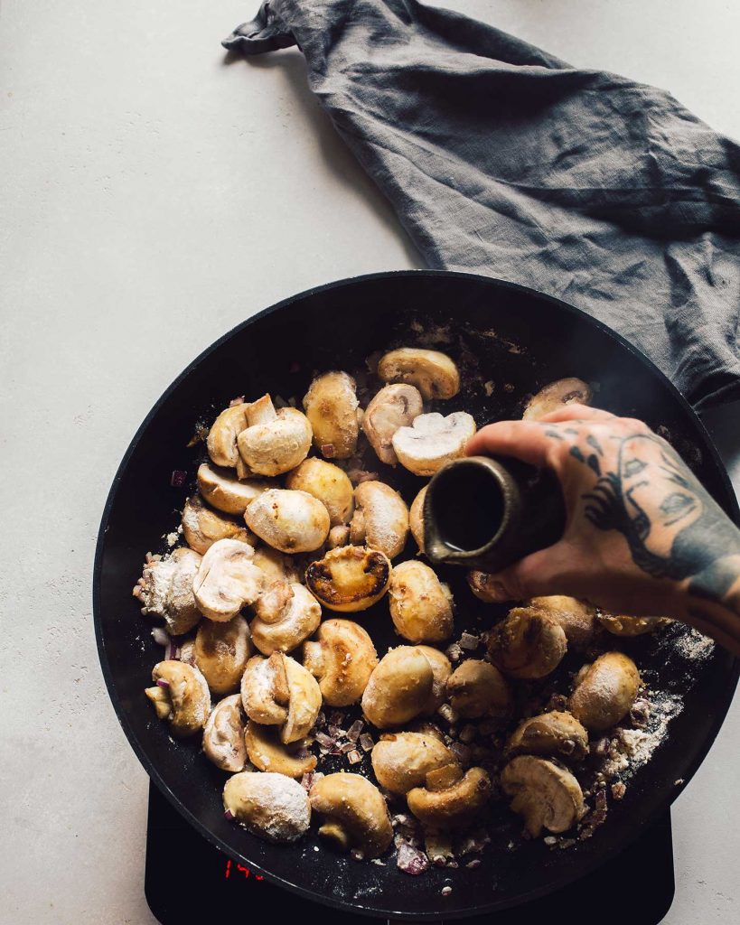 Vegane Spinatknödel serviert mit cremigen Rahmchampignons auf einem Teller