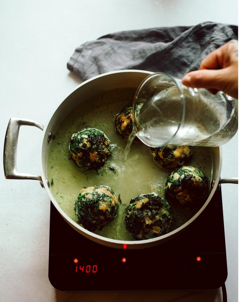 Vegane Spinatknödel serviert mit cremigen Rahmchampignons auf einem Teller