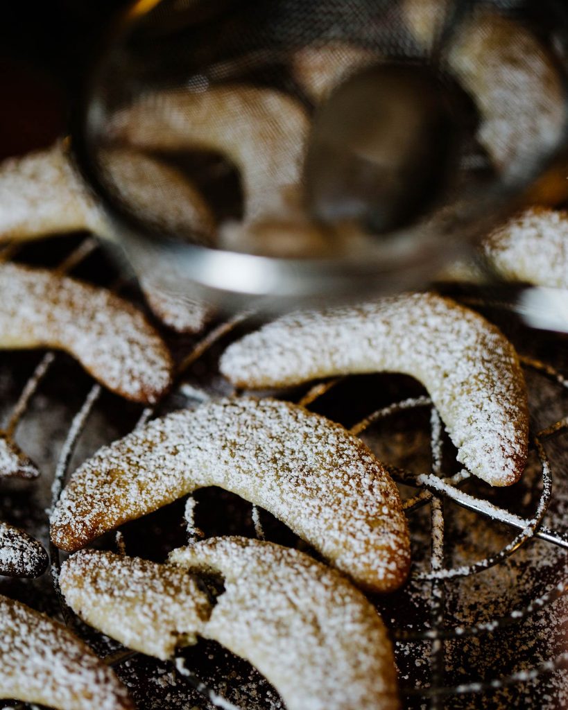 Vegane Vanillekipferl auf Backpapier mit Puderzucker bestäubt