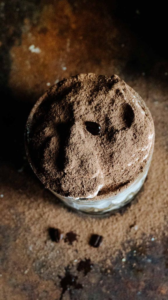 Veganes Tiramisu im Glas mit Kakao bestäubt auf einem Dessertteller