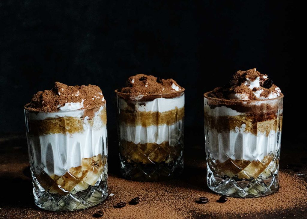 Veganes Tiramisu im Glas mit Kakao bestäubt auf einem Dessertteller