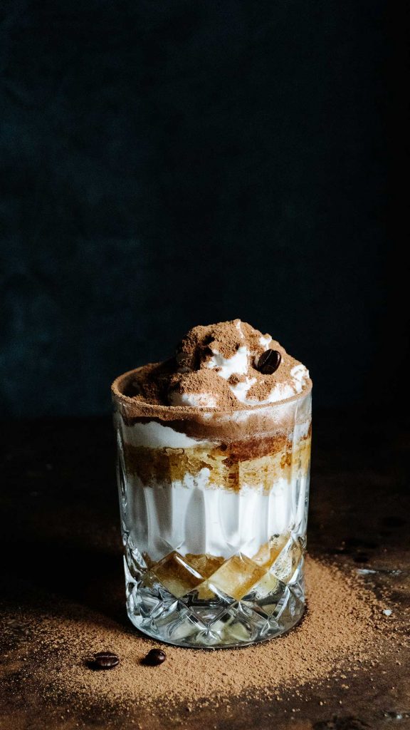 Veganes Tiramisu im Glas mit Kakao bestäubt auf einem Dessertteller